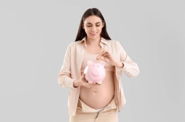 Genç hamile bir kadın arka planda kumbaraya para koyuyor. Annelik Faydası kavramı