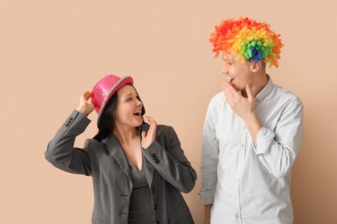 Parti şapkalı ve bej arka planda palyaço peruğu takan iş adamları. 1 Nisan Kutlaması