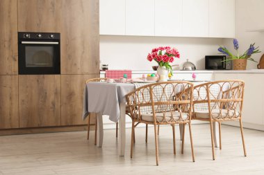 Paskalya yumurtaları, laleler ve yemek takımlarıyla dolu yemek masası.