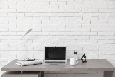 Beyaz duvarın yanında lamba ve dizüstü bilgisayarı olan modern işyeri