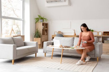 Evde defterine para yazan hamile bir kadın var. Annelik Faydası kavramı