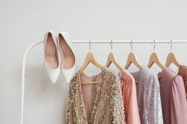 Beyaz duvarın yanında şık elbiseler ve şık topuklu ayakkabılar.