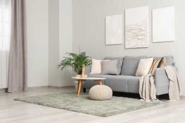 Oturma odasının içinde kanepe, resimler ve kahve masası var.