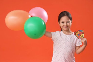 Turuncu arka planda balon ve kağıt balıklı şirin bir kız. 1 Nisan şakası
