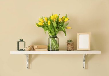 Oturma odasındaki rafta kitap bulunan lale vazoları.