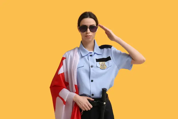 Saluting female police officer with flag of Canada on yellow background