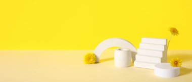 Sarı zemin üzerinde karahindiba çiçekleri olan dekoratif podyumlar.