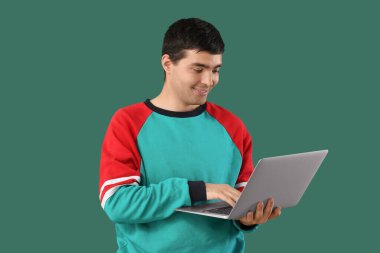 Yeşil arka planda dizüstü bilgisayarla çalışan erkek programcı