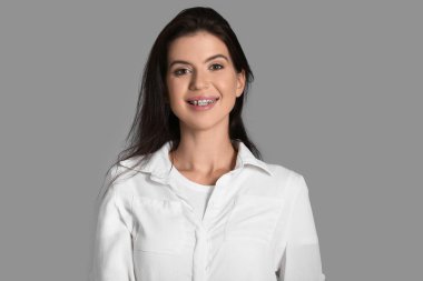 Gri arka planda diş telleri olan genç bir kadın.