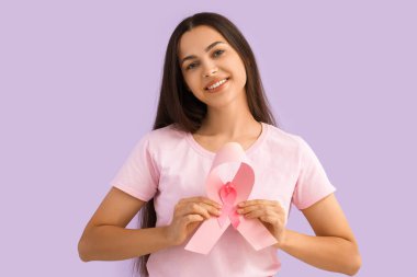 Leylak arka planında pembe kurdeleli genç bir kadın. Göğüs kanseri farkındalığı konsepti