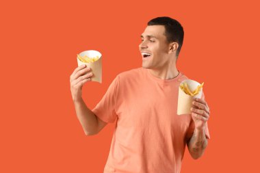 Turuncu arka planda patates kızartması olan genç bir adam.