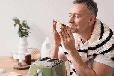 Mutfakta kızarmış ekmeği olan orta yaşlı bir adam.