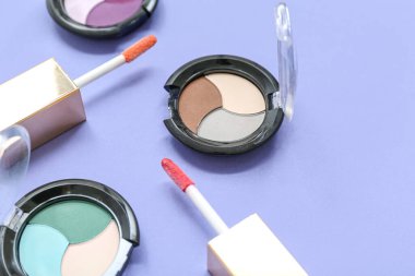 Leylak arka planında dudak parlatıcısı fırçasıyla farklı göz falı paletleri