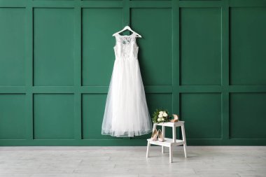 Güzel gelinlik yeşil duvarda yüzük kutusu, düğün ayakkabıları ve beyaz tahta merdiven üzerinde gelin buketi.