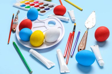 Paskalya yumurtaları, kalemler ve renk arkaplanlı boya paletiyle kompozisyon. Paskalya konsepti.