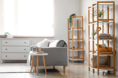 Masa, kanepe ve pencerenin yanındaki ahşap raflar.