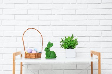 Sepete boyanmış yumurta, okaliptüs bitkisi ve tuğla duvarın yanındaki rafta Paskalya tavşanı.