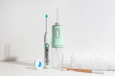 Beyaz arka planda ağız temizleyici, elektrikli diş fırçası, havlu ve diş ipi.