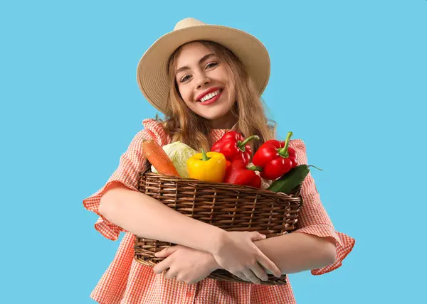 Junge Bäuerin Mit Frischem Gemüse Weidenkorb Auf Blauem Hintergrund — Stockfoto