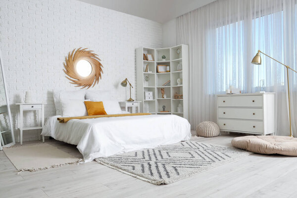 Интерьер светлой спальни с большой кроватью, зеркалом и полкой