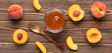 Kavanoz dolusu tatlı şeftali reçeli, kaşık ve taze meyve ahşap arka planda, üst manzara