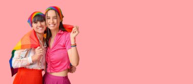 Pembe arka planda LGBT bayrağı olan genç lezbiyen çift ve mesaj için yer