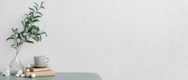 Bitki dalları, Paskalya yumurtaları, tavşancık ve beyaz duvarın yanında fincanı olan vazo. Tasarım için pankart