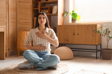 Genç kadın evde meditasyon yapıyor.