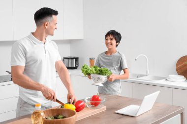 Babası mutfakta yemek yapan küçük bir çocuk.