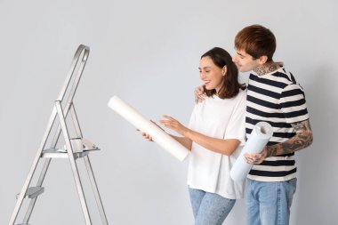 Duvar kâğıdı ruloları olan genç bir çift yeni evlerinde tamirat yapıyor.