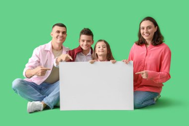 Ebeveynleri ve yeşil arka planda boş posterleri olan küçük çocuklar.
