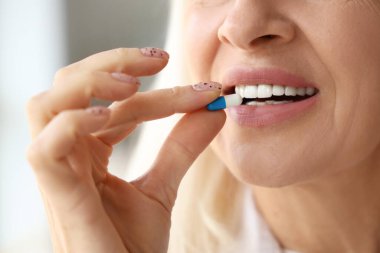 Evde hap alan olgun bir kadın, yakın plan.