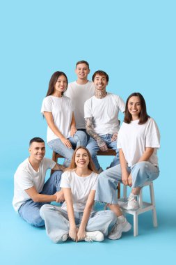 Mavi arka planda şık kotlu bir grup genç.