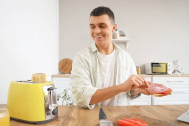 Genç adam mutfakta tost yaparak lezzetli sandviçler yapıyor.