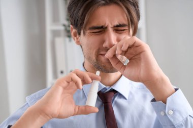 Hasta işadamı ofiste burun damlası kullanıyor, yakın plan.