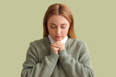 Olgun kadın yeşil arka planda dua ediyor, yakın plan