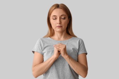 Olgun bir kadın arka planda dua ediyor