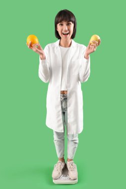 Yeşil arka planda kilolu meyvelerle beslenen kadın beslenme uzmanı. Diyet kavramı