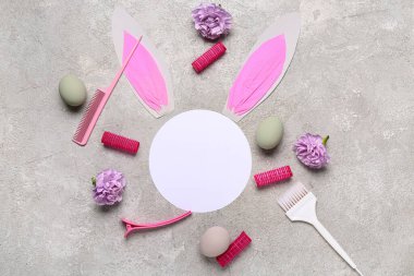 Gri grunge arka planında kuaför aksesuarları, çiçekler ve Paskalya dekoru olan boş bir kart.