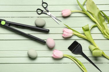 Yeşil ahşap arka planda lale ve Paskalya yumurtalarıyla kuaför aksesuarları.