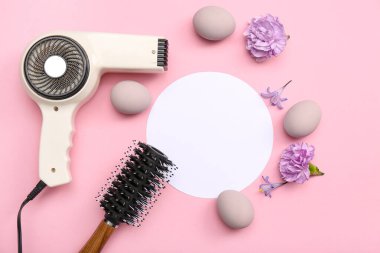 Kuaför aksesuarları, çiçekler ve pembe arka planda Paskalya yumurtaları olan boş bir kart.