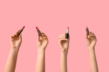 Pembe arka planda farklı ruj izleri olan kadın elleri.