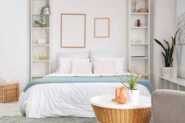 Büyük yataklı, raf üniteli ve çerçeveli aydınlık yatak odasının içi