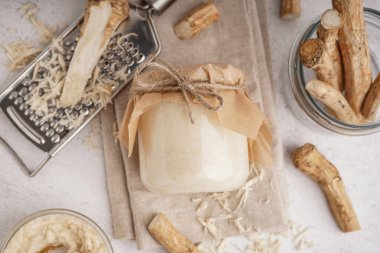 Beyaz arka planda yabanturpu kökleri olan yabanturpu sosu kavanozu. Üst görünüm