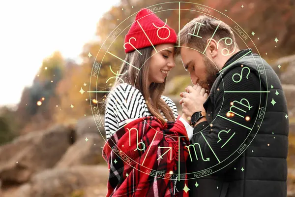 Young man kissing his girlfriend\'s hands in beautiful autumn park. Love compatibility horoscope. Partner matching by date of birth