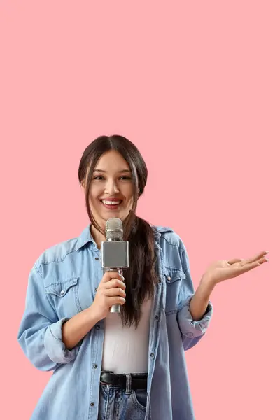 stock image Female Asian journalist with microphone talking on pink background