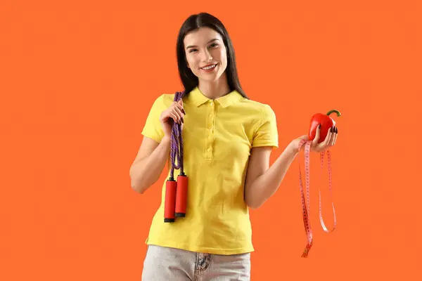 オレンジ色のバックグラウンドでロープ ベルペッパー テープをスキップした若い女性 ダイエットコンセプト — ストック写真