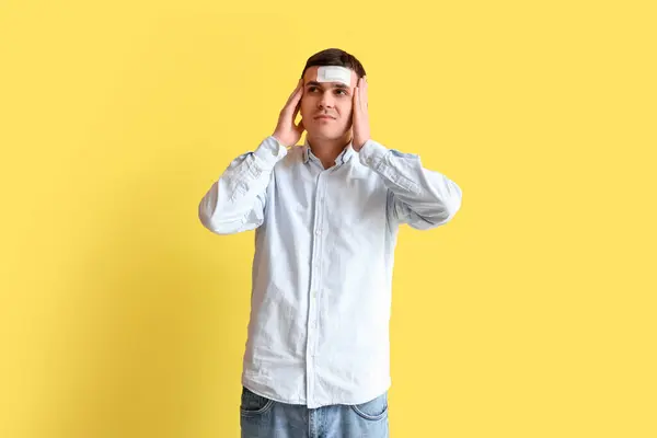 Junger Mann Mit Gehirnerschütterung Und Medizinischem Pflaster Auf Gelbem Hintergrund — Stockfoto