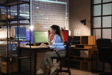 Geceleri ofiste çalışan, bilgisayar monitörlü bir Afro-Amerikan kadın programcı.