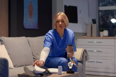 Akşamları hastanedeki kanepede oturan kahve fincanlı kadın hemşire.